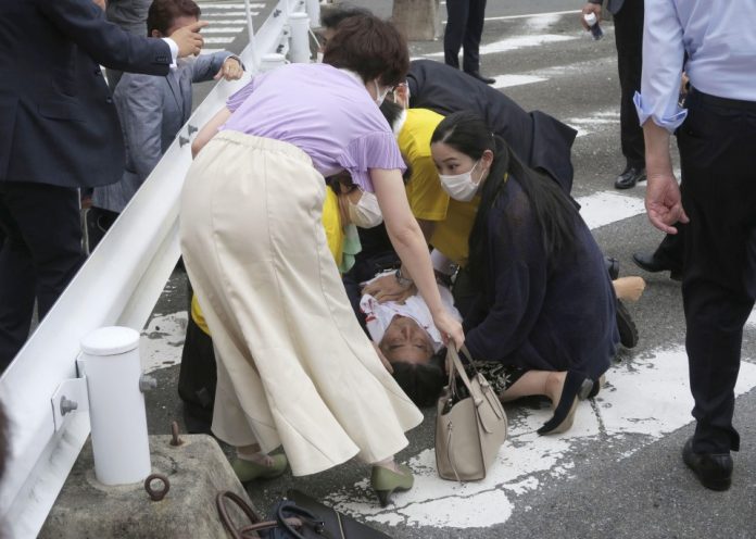 Former Japanese Prime Minister Shinzo Abe (C) lies on the ground on the side of a road after being shot by a gunman while delivering a stump speech in Nara, western Japan, on July 8, 2022, ahead of the July 10 House of Councillors election. (Kyodo)