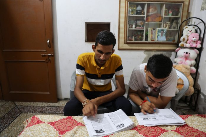 Vijay Chauhan, 18, and Vishal, 18, who both take English language classes at Western Overseas institute, go through their notes at Vijay's house in the village of Adhoya in Ambala district, India, August 15, 2022.